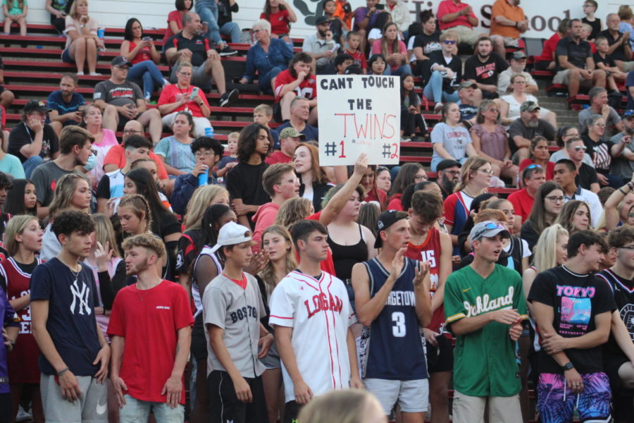A student holds a homemade sign as she cheers on juniors Shamari and Amari Gittings.