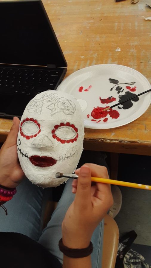 Daisy Pablo estudiante de primer año elige hacer la Máscara Mexicana del Día de Muertos y la está pintando de rojo.