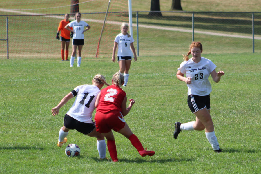 (Above) Junior Cassidy Cuppy wears her red home jersey as she tries to take the ball away from a South Adam player. 