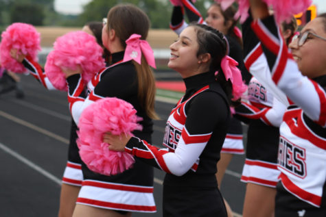 Using her pom-poms, junior Emily Sanchez smiles at the crowd between chants.