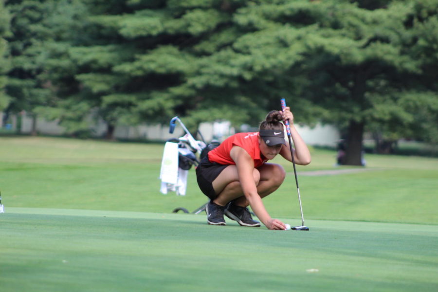 Lining up the golf ball, senior Myleigh Moon is focusing on where her ball is going to break to drop into the hole. 