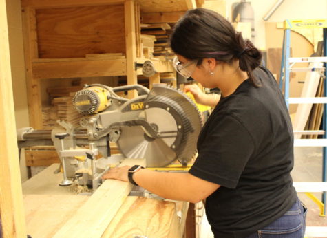 Sophomore Valeria Cortes uses a circular saw to cut a piece of wood to use for the “Mamma Mia!” set. 