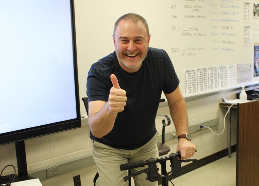 While on his scooter due to having surgery, advanced U.S. History and Geography teacher, Bryan Looker holds a thumbs up. 