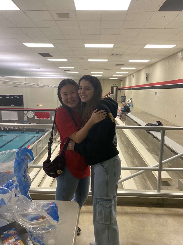 Foreign Exchange Students Xenia Ortega Romeu and Marilynn Cucci embrace near their shared activity, swimming.