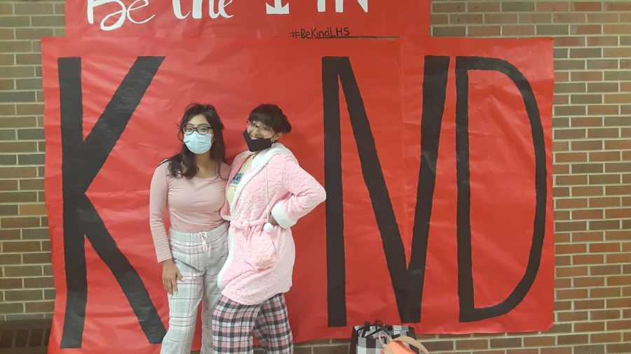 Juniors Lynette Cruz and Luna Tafolla posing on Pajama Day in front of the kindness poster.
