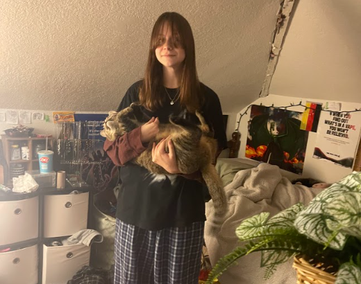 Holding their cat Sonny, freshman Mara Rieger stands in the middle of their room. Sonny was a stray that Rieger started taking care of back in June 2022.