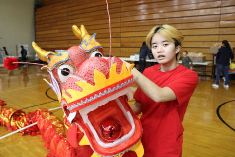 Sophomore Kiara DeInnocentes poses with the head of the dragon. DeInnocentes is the coach for the Dragon team and performed at the half-time Lunar New Year celebration at the Twin Lakes basketball game. 