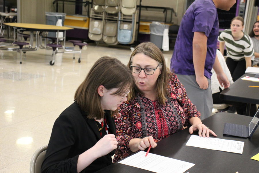 Junior Carissa Dawson receives her total score from her designated adult at a spell bowl competition. At these in-person competitions, the speller writes down the five words theyre assigned and after, their adult supervisor checks their accuracy.