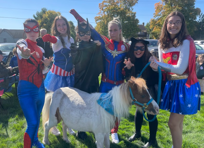 At the Woodbridge Fall Fest, the superheroes pose with a pony before going into the smoke house with a group of kids.