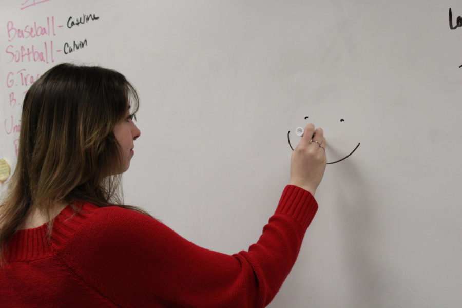 Sophomore Ella Weathers draws a smiley face on the whiteboard.