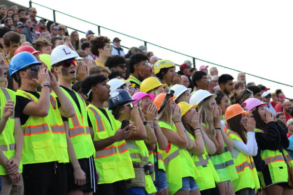 Wearing bright safety vests and hard hats, the student section hollers at their first official home football game. At every home game, there is a theme for what to wear to the game. The theme of this specific game was construction.