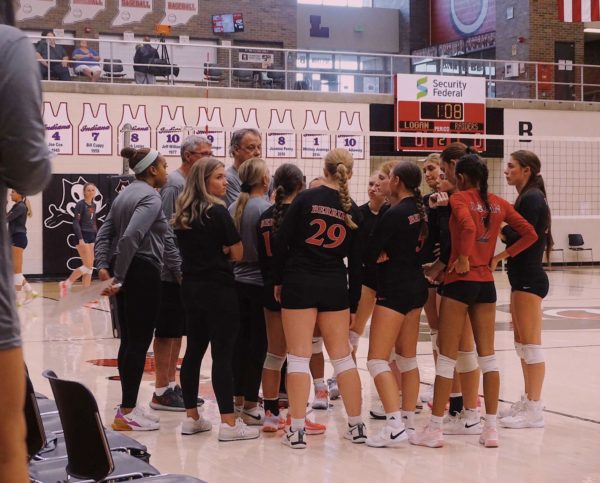 The Lady Berries huddle around Coach Long to receive constructive criticism on the previous set.