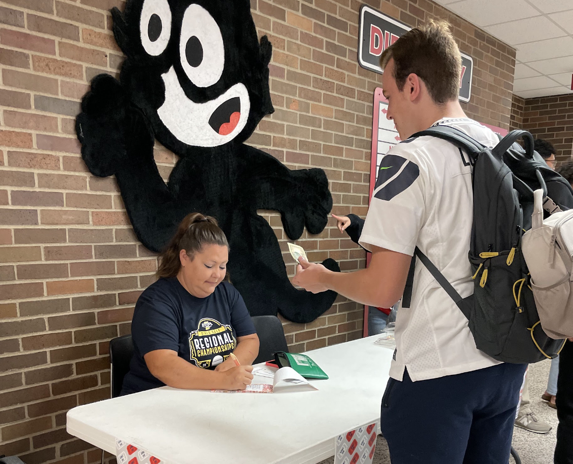 Outside of the main office, Abby Lundy sells a ticket to senior Finley Gay. Tickets have beeen sold all week for students to buy.