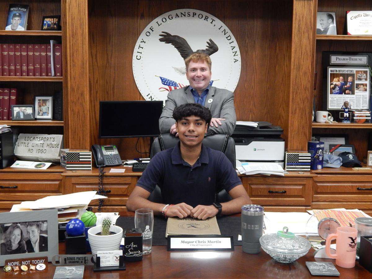 Sitting at Logansport Mayor Chris Martin's desk while Martin stands behind him, Patel and Martin pose for a picture. Patel became Martin's intern at the beginning of the school year. 