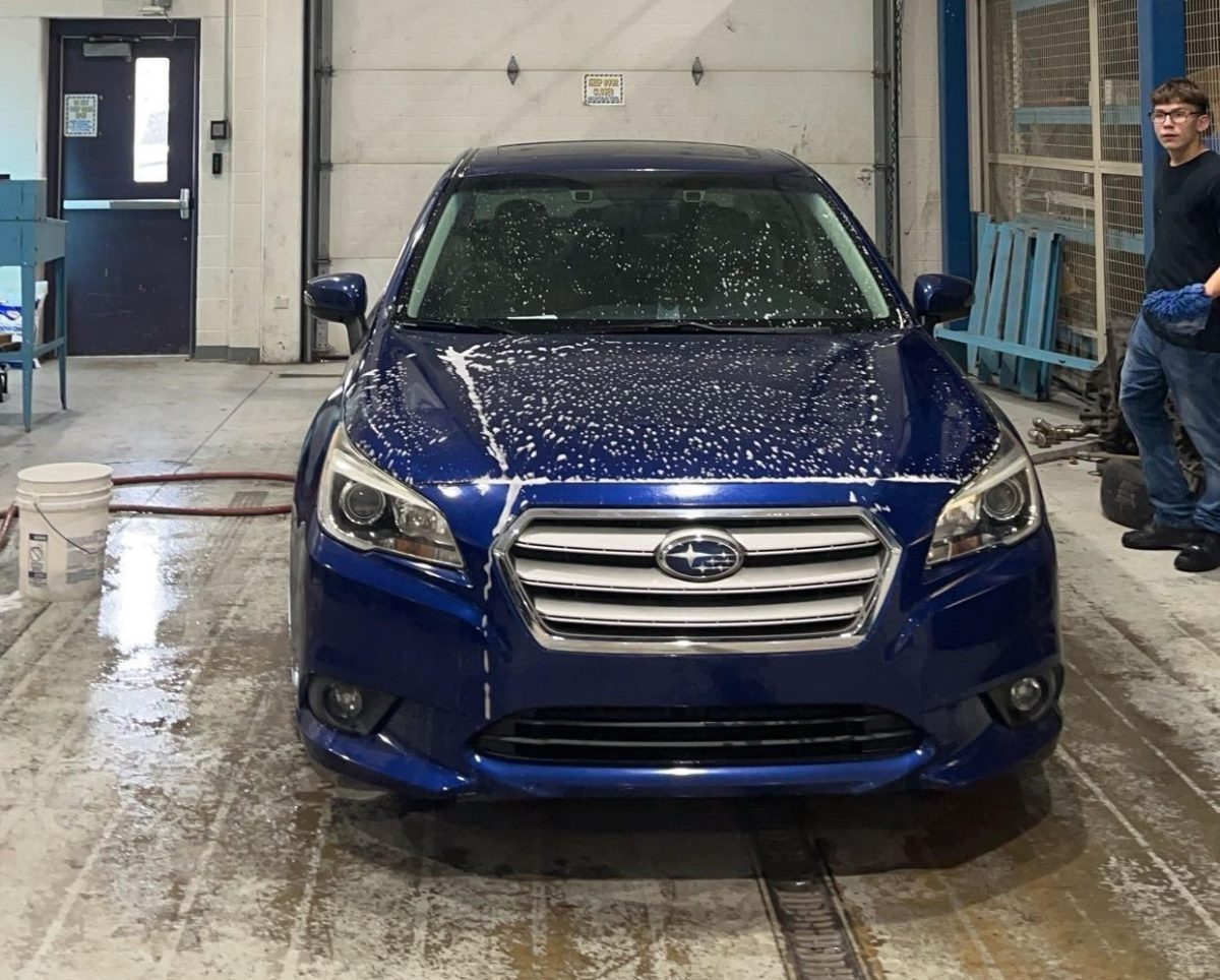A freshly washed Subaru Legacy parked inside of the auto service garage.