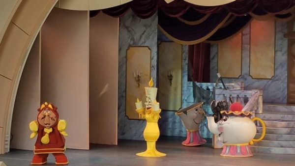 Characters from Beauty and the Beast dance around the stage.