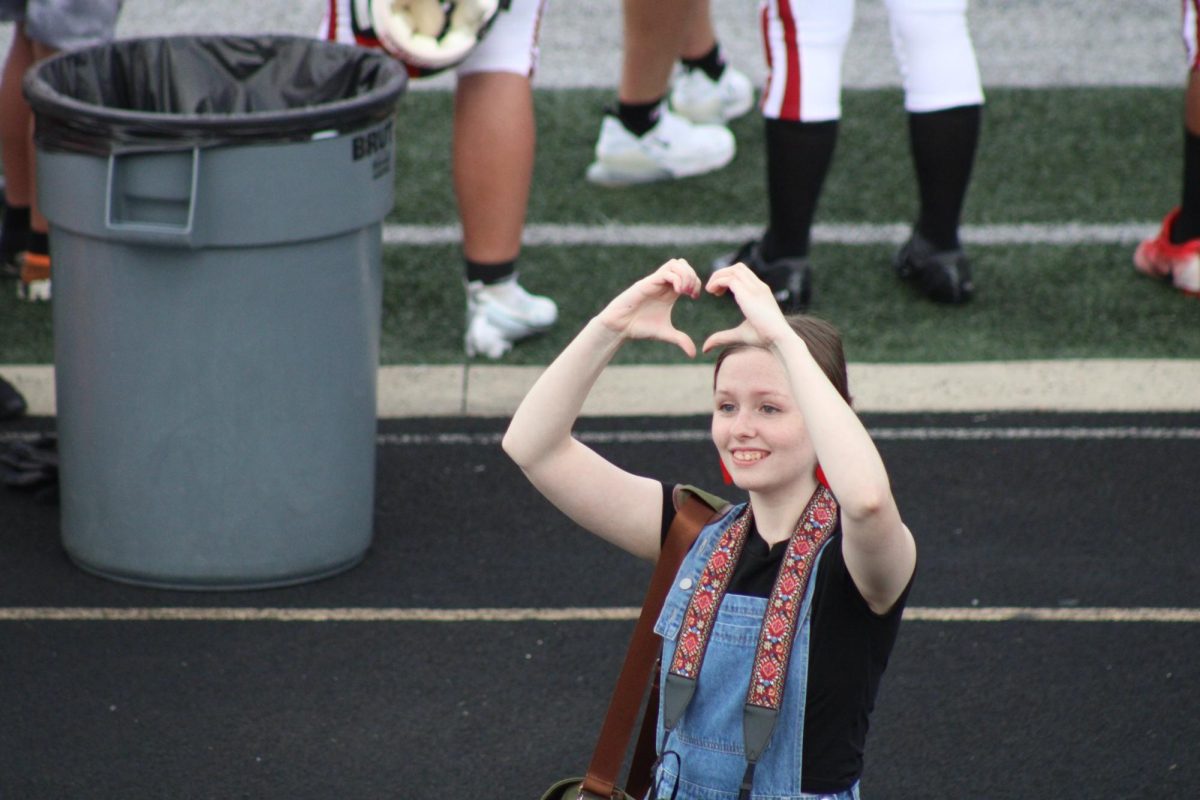At+a+football+game%2C+senior+Gretchen+Prifogle+takes+a+break+from+taking+pictures+to+show+school+spirit.+