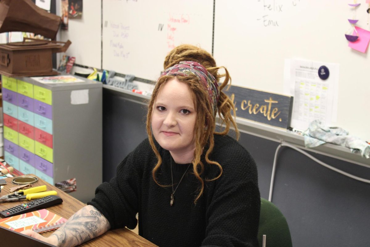 Nicole Ingalls, the director of the Art Club, sits at her desk, surrounded by her students and her own creations.