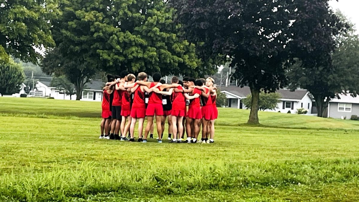 The boys cross country team huddles together before getting ready to race.