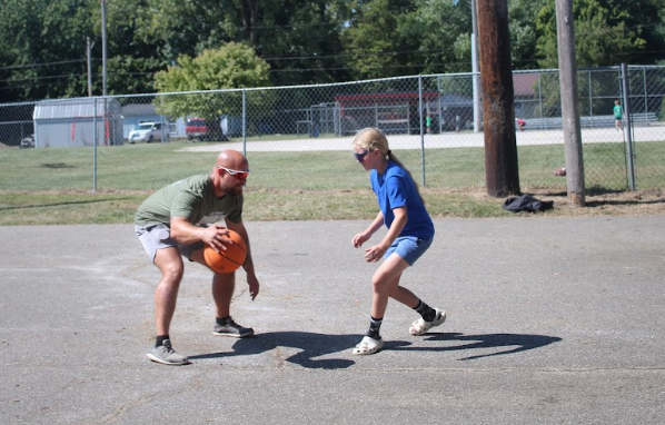 Palmer moves to the basket while dribbling the ball against a student, engaging in active play with the students in addition to providing them with coaching is a way he creates strong bonds with athletes.