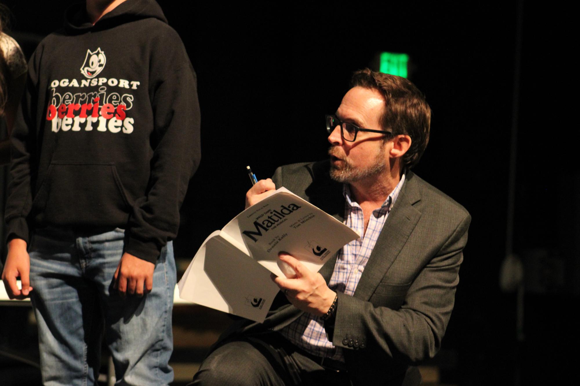 Kneeling, Director Anthony Kinney shows the cast playing children how he wants them to take the balloons from the children's entertainer in the opening number. (Chris Pearcy)