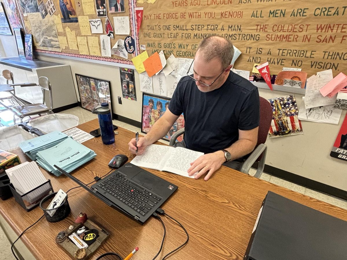 Hard at work, history teacher Bryan Looker grades an essay at his desk. Each semester, students are required to write four essays in his class.