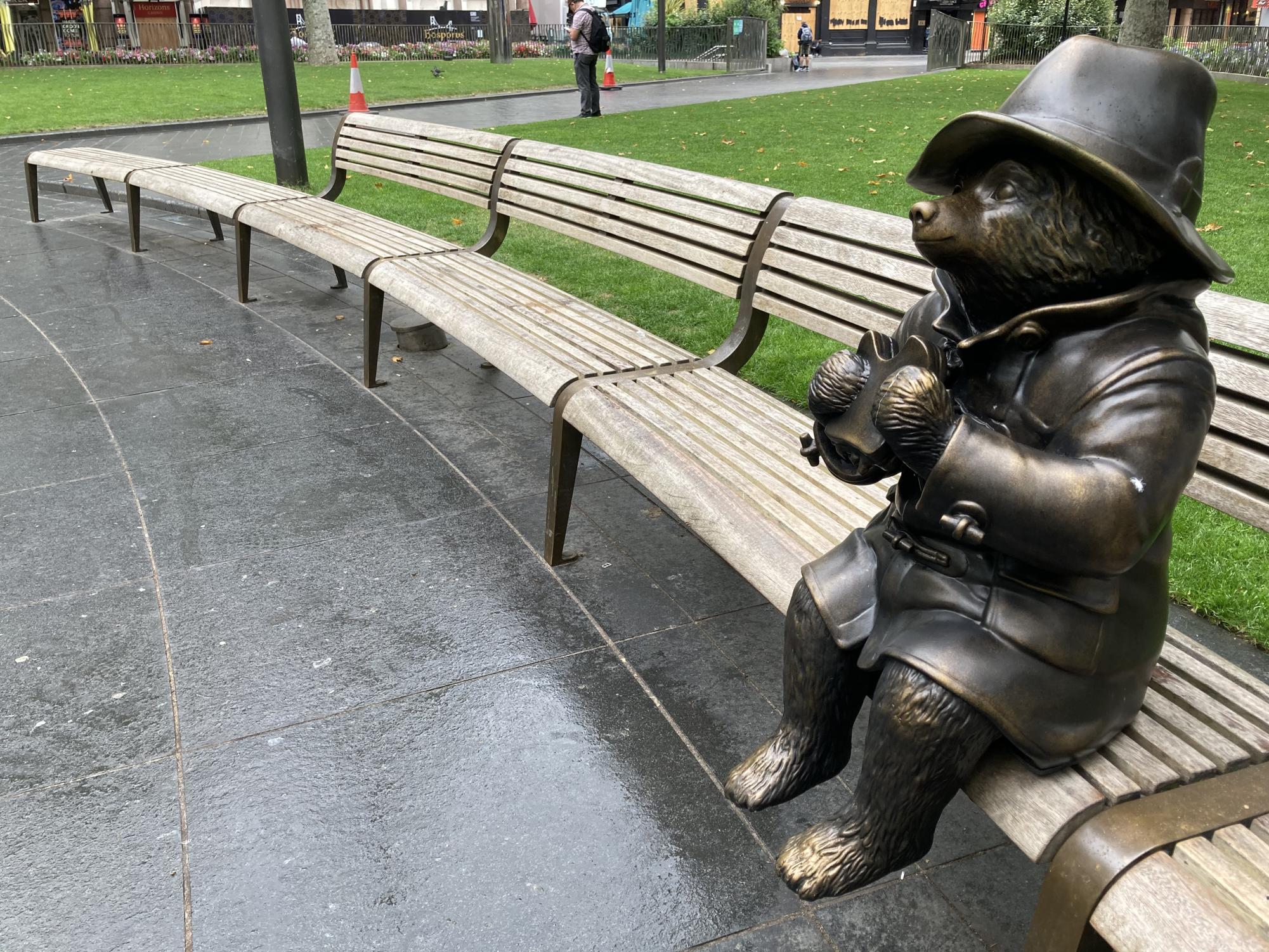 In London, Paddington Bear is sitting on a bench eating his marmalade sandwich.