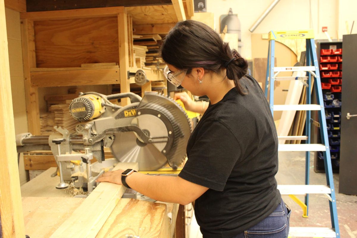 Senior Valeria Cortes uses a saw to cut a piece of wood.
