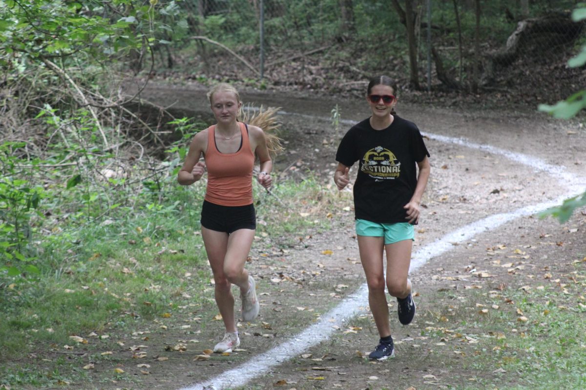 Junior Katelynn Spradling and sophomore Alette Woodhouse run during their main workout inside the Berry Patch.