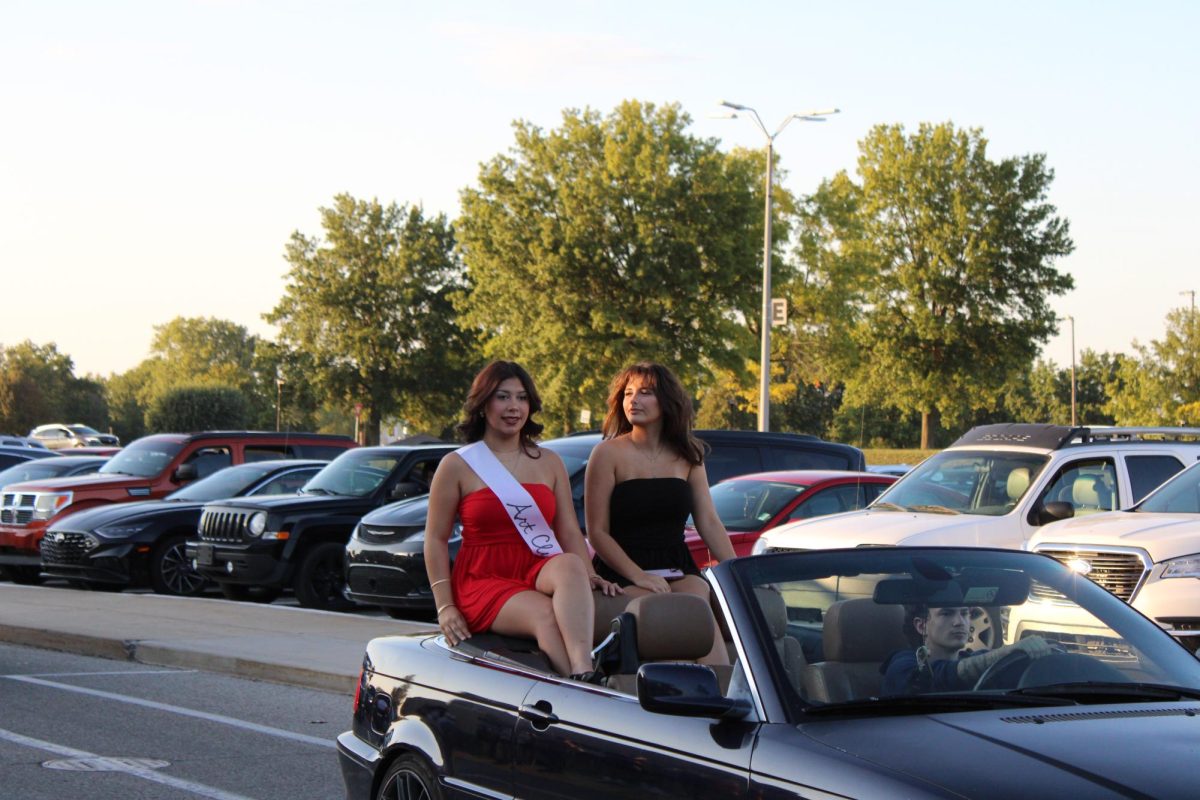 Escorted by senior Layla Lawhead and representing Art Club, senior Gianna Williamson smiles at the crowd.