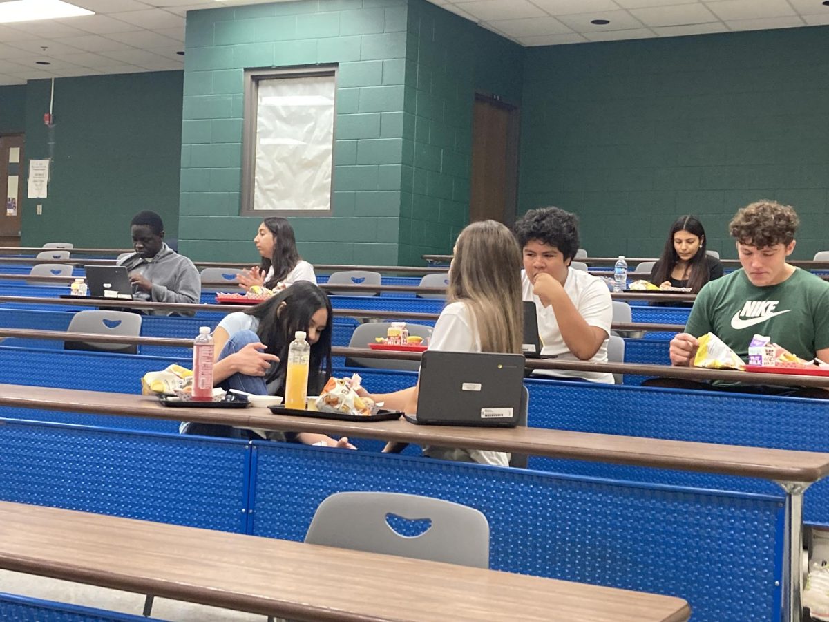 Students in a lecture hall working together on their schoolwork during lunch.