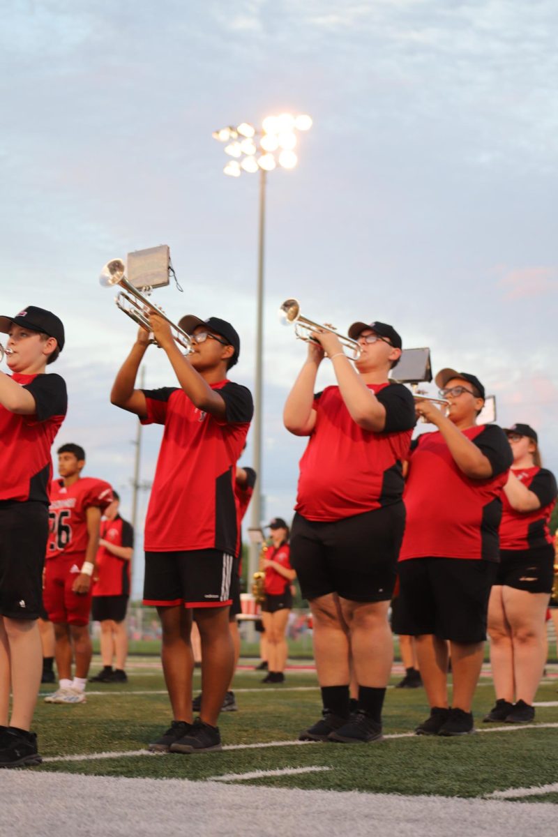 The Logansport High School Marching Band plays underneath the lights at a football game.