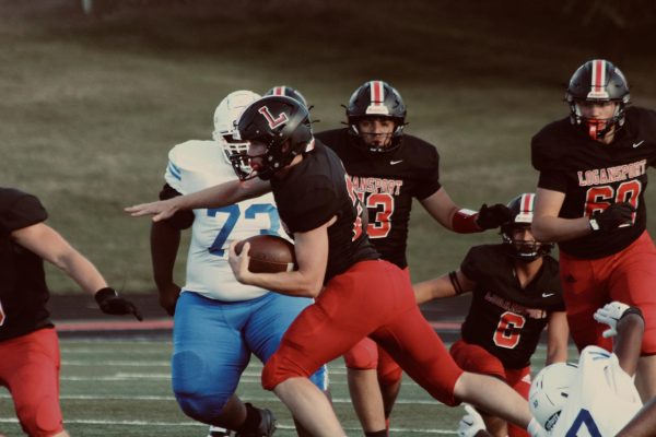 Running back Elliot Baldini carries the ball past defenders against the South Bend Adams Eagles. The Berries went on to defeat the Eagles 54-6.