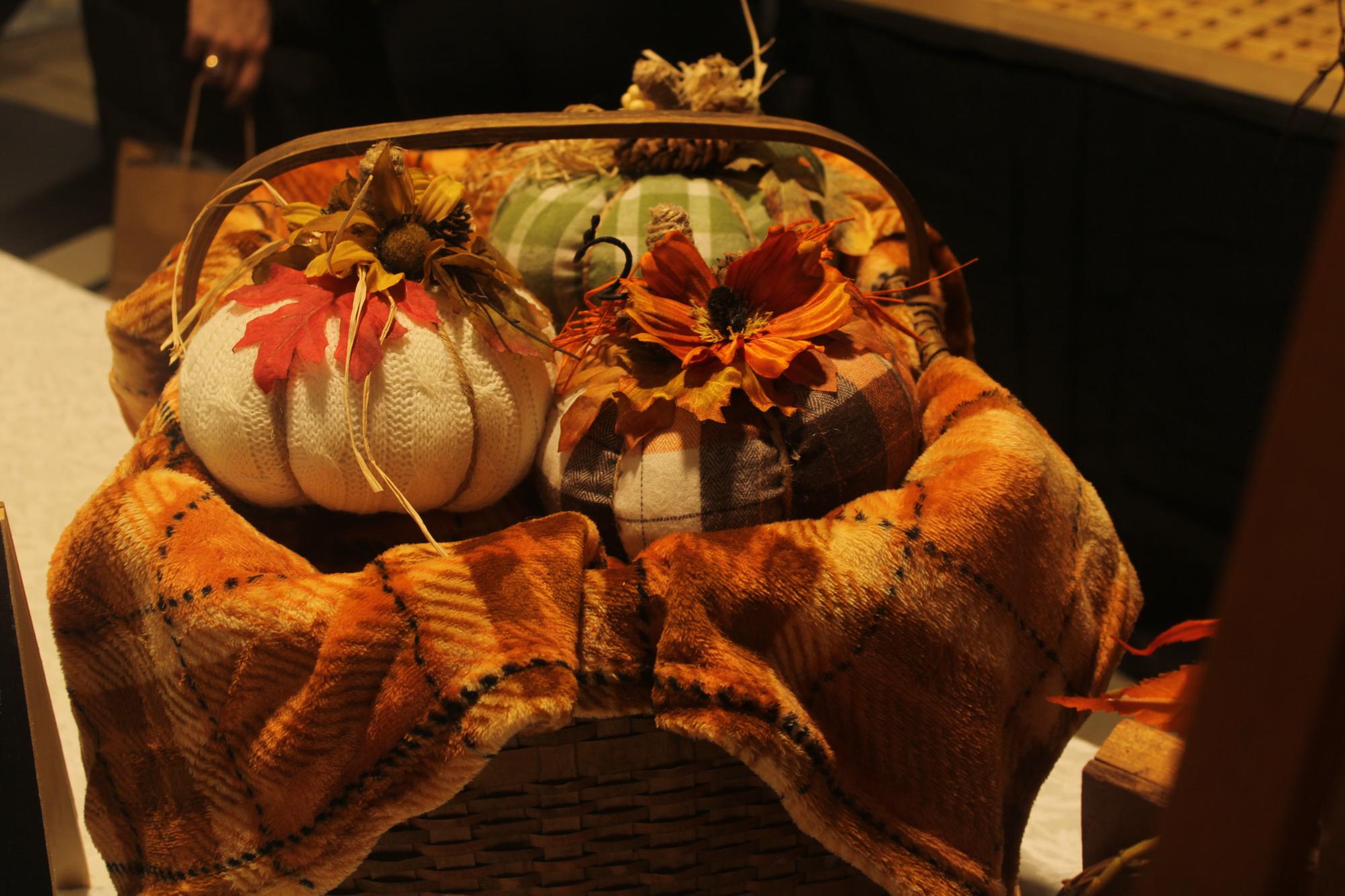 A basket of home made pumpkins in a basket. Made with things like fabric and string. 