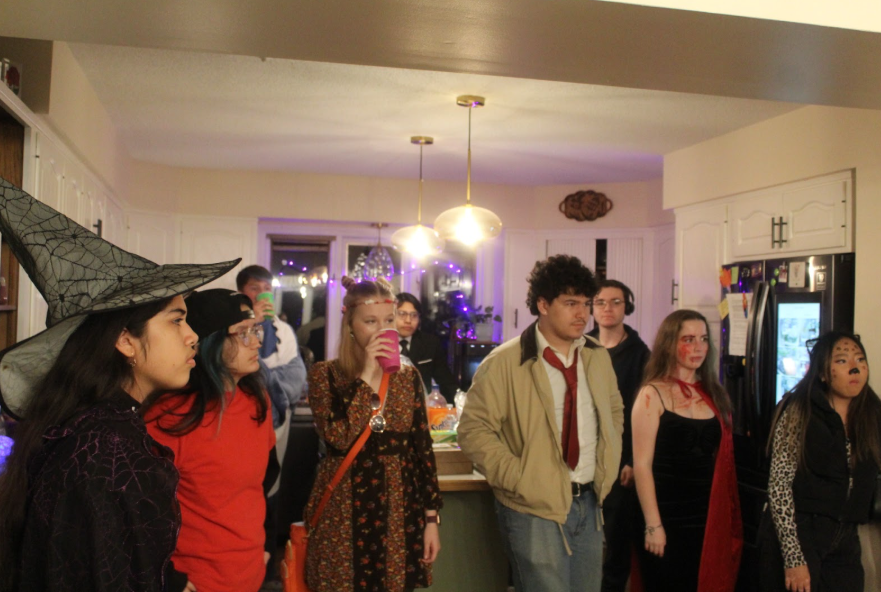 Everyone grouped together to talk about a costume competition, in their variety of Halloween costumes. Just one of many events of the night. 