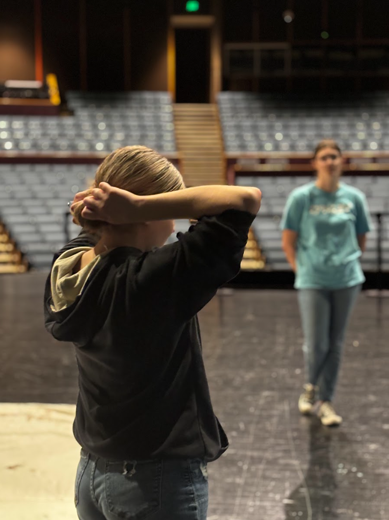 Senior Shelby Ping fixes her hair as she discusses drop fold strategy with her team.