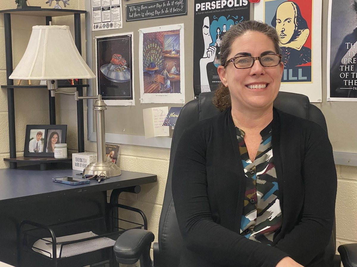English teacher Amanda Kitchell smiles while sitting at her desk.