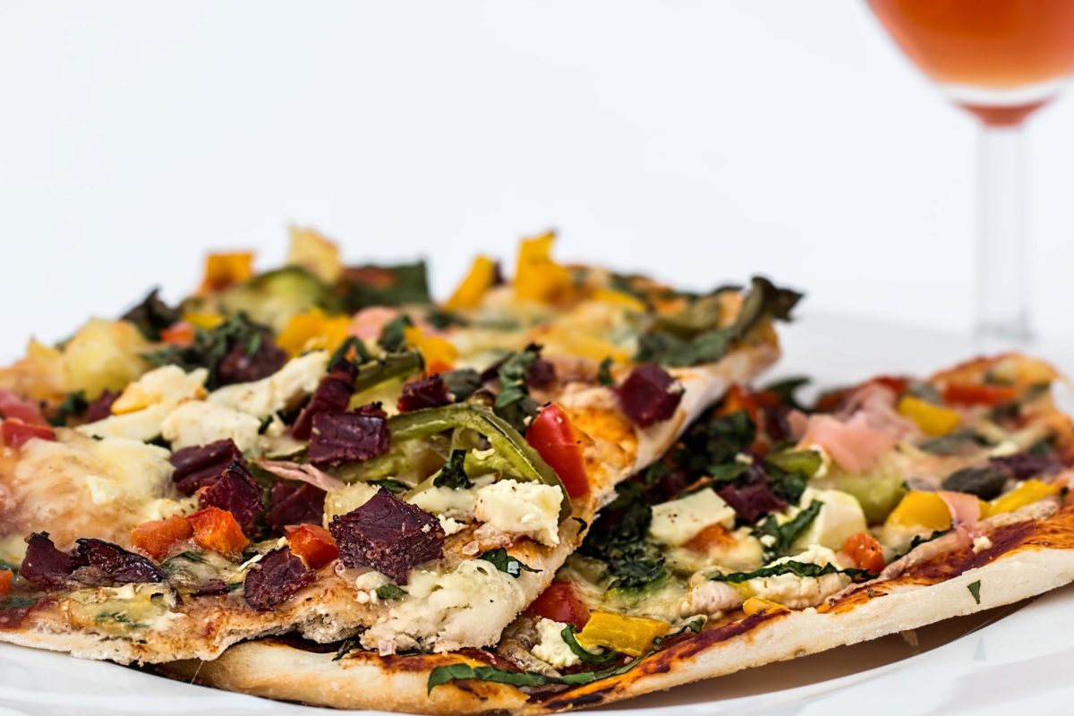 A vegetable flatbread pizza topped with feta cheese and colorful peppers sits on a white plate. (Pixabay)