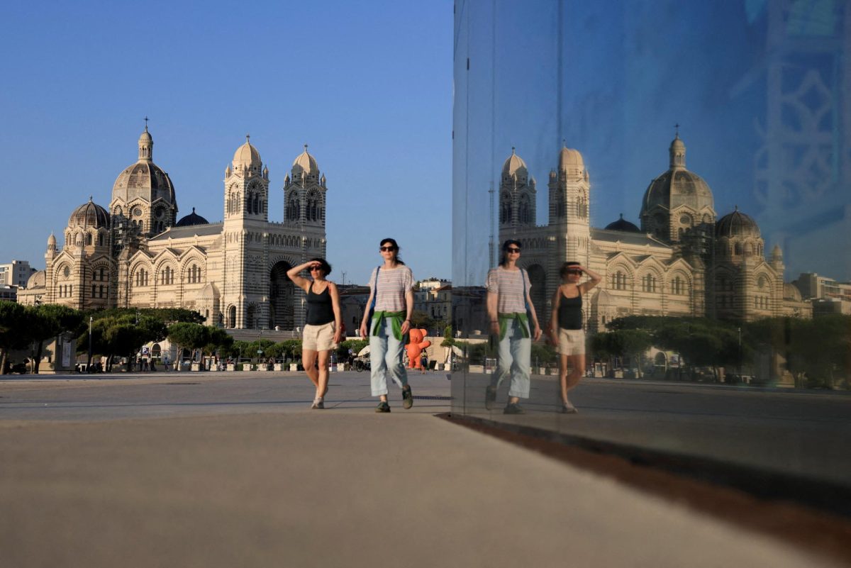 Women walk past the reflection of the Cathedrale de la Major in Marseille, France, August 5, 2025. REUTERS/Manon Cruz