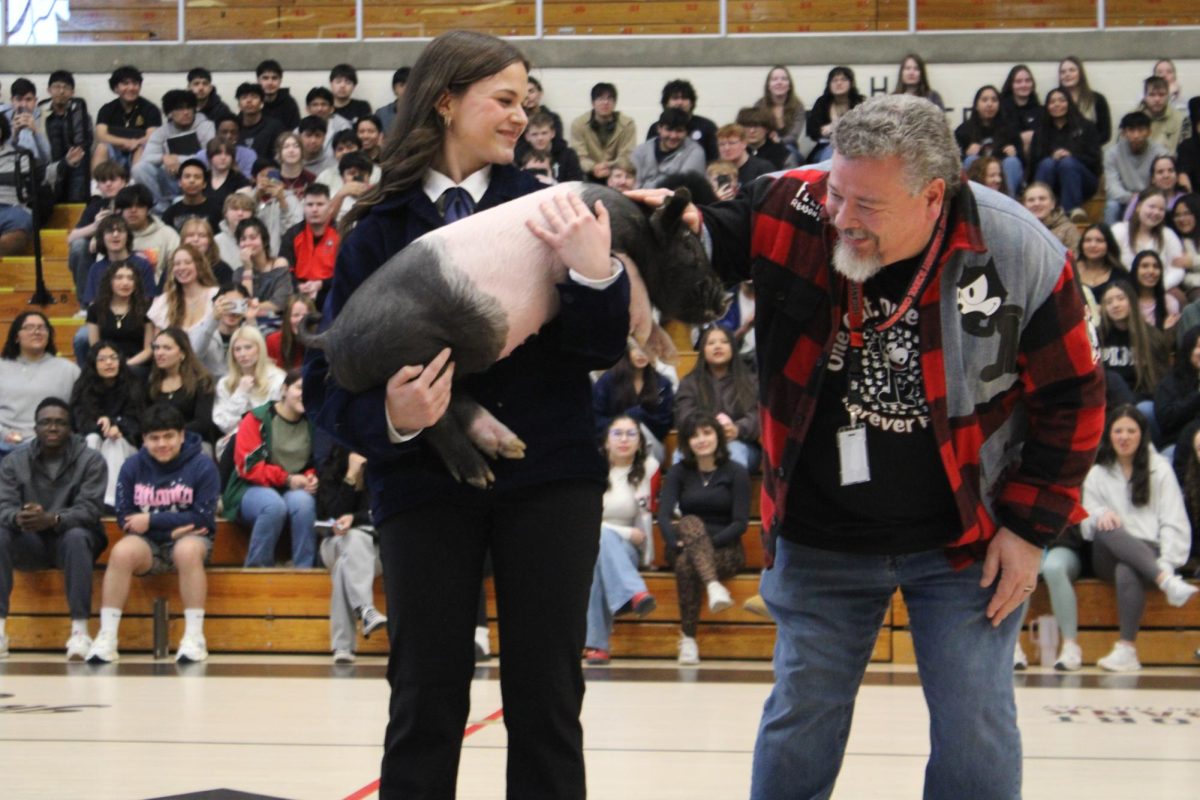 Accepting his fate, physics teacher Benjamin Huntington pets Paisley the Pig before giving her a smooch. 