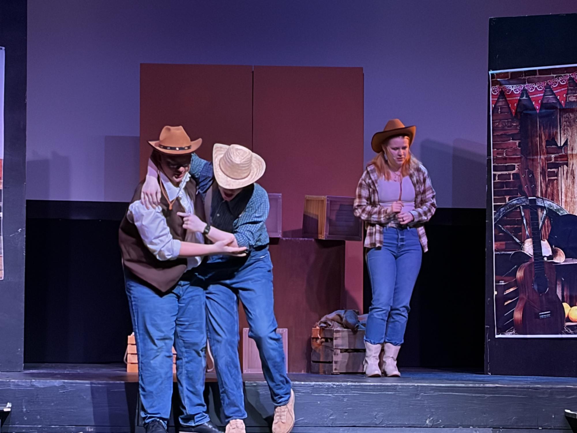 Sheriff Tickle (played by senior Calvin Mackey) is caught off guard by Milton (played by junior Chris Knapp) who just ran to him from the audience. The sheriff's daughter, Sarah (played by sophomore Molly Hunnicutt) watches the encounter with disgust.