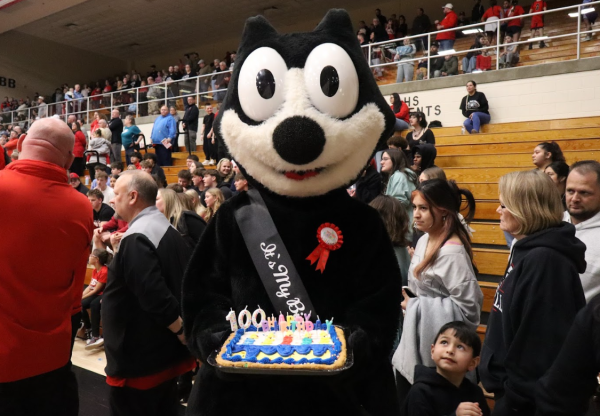 Mascot Felix the Cat holding his birthday cake during a basketball game in the Berry Bowl.