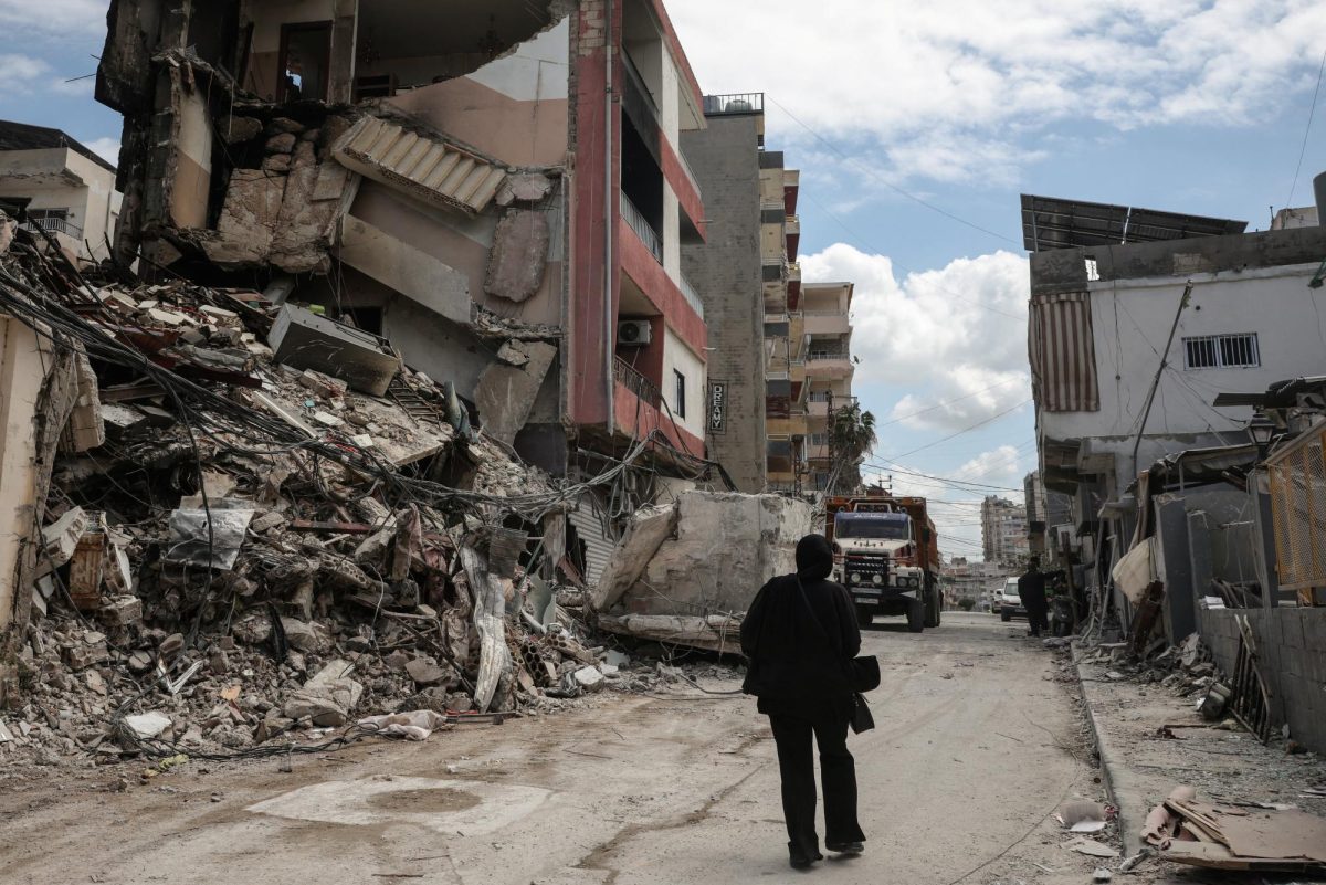 A woman walks past buildings, destroyed during Israeli strikes last Wednesday, in Tyre, Lebanon, April 10, 2026. REUTERS/Louisa Gouliamaki