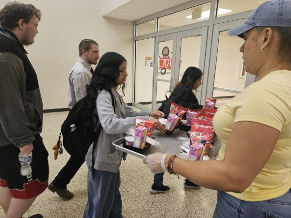 As they enter the school's doors, students grab the handed breakfast from Evel Duran.